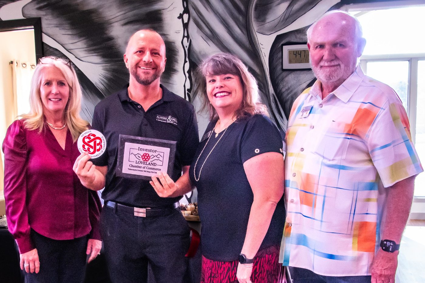 Dr. Brian Flemming with Loveland Chamber of Commerce members holding the Chamber plaque at Aligned and Well